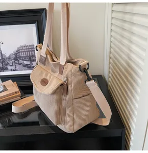 Detailed view of casual beige corduroy tote bag featuring front pocket and adjustable strap.