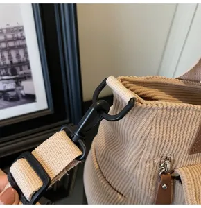Corduroy shoulder bag detail shot showing black metal hardware, adjustable strap and zipper pocket.