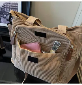 Detailed close-up view of a stylish beige corduroy tote bag with handy front pockets.