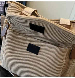 Detailed view of the casual beige corduroy tote bag with zipper and front pocket design.