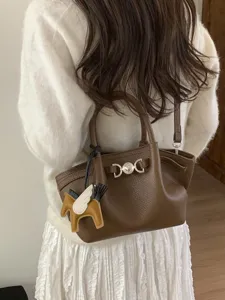 Stylish brown leather tote shoulder bag for women, chic bucket handbag with winged horse charm.