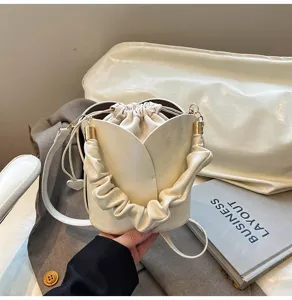 Elegant tulip bucket bag with drawstring inner pouch and metal handle details for women.