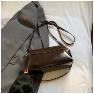 Detailed view of the dark brown wrinkled leather shoulder bag styled with a blazer.