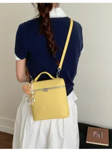Vue détaillée du sac à bandoulière jaune élégant en boîte avec charmant pendentif.