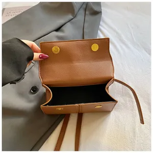 Élégante sac à bandoulière pour femme en cuir marron avec des boutons magnétiques dorés.