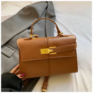 Vue rapprochée d'un élégant sac à main marron avec serrure dorée et poignée solide.