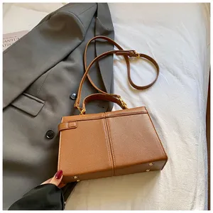 Gros plan détaillé montrant la texture du sac à main en cuir marron avec accessoires dorés.