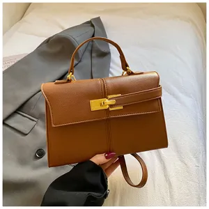 Détail de sac à main rigide en cuir marron avec fermoir tournant doré et design rétro.