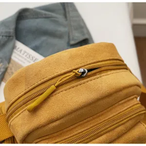 Close-up view of the yellow suede camera bag zipper detail, showcasing premium texture.