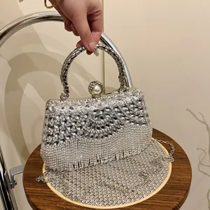 Rhinestone evening bag detail showing sparkling crystals, pearl clasp, and metal fringe.