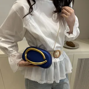 Nahaufnahme der eleganten blauen Kapsel-Abendtasche mit auffallendem goldenen Griff.