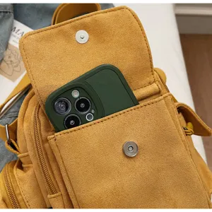 Close-up of yellow suede crossbody camera bag featuring front pocket and phone storage.