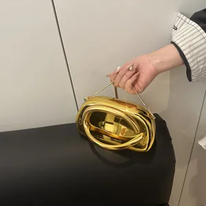 Detailaufnahme einer goldenen Metallic-Abendtasche mit einzigartigem Ring-Design.