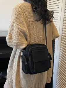 Black canvas cross-body camera bag for women, versatile messenger bag with multiple pockets.
