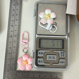 Cherry blossom keychain detail view showing product size and weight measurement on scale.
