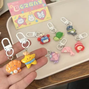 Close-up detail of cute resin marine life keychains featuring starfish and shells on tray.