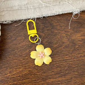 Yellow cherry blossom keychain pendant detail, cute floral accessory design on wood background