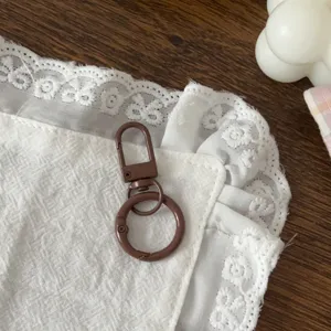 Primo piano dettagliato del moschettone a molla marrone e anello per accessori fai da te.