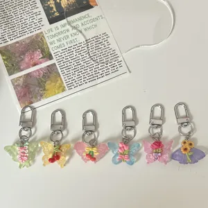 Detailopname van kleurrijke hars vlinder sleutelhangers met schattige bloemen hangers.