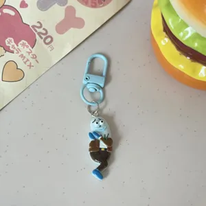 Close-up of a cute cartoon blue character keychain pendant with brown jacket, detailed design.