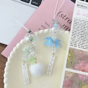 Detailed view of handmade jasmine bell and snow maple leaf phone charm and bag accessory.