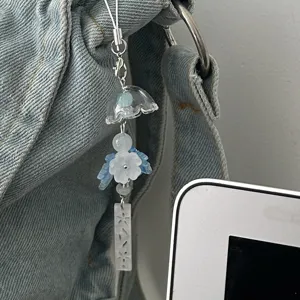 Close-up detail of transparent glass windchime and blue flower bag charm pendant.