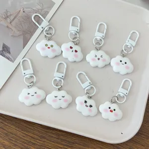 Cute white cloud keychains set with adorable facial expressions and pink blush, detail view.