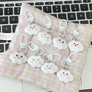 Detailed shot of cute cloud keychains with various expressions on a pink plaid cushion.