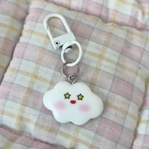 Close-up detail of cute white cloud keychain with star eyes and blush pendant for bags and keys.