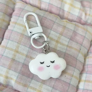 Cute cloud keychain pendant with cute smiling face expression, soft blush design, white clasp charm.
