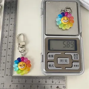 Detailed view of colorful rainbow flower emoji keychain showing weight and size scale.