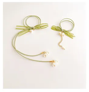 Primo piano dettagliato del legaricci capelli con fiocco mughetto verde e nastro.