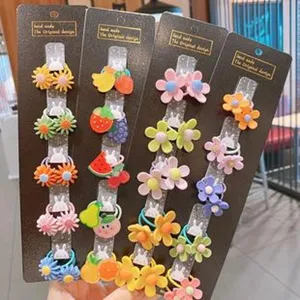 Primo piano dettagliato di elastici per capelli colorati con fiori e frutta su cartoncini espositivi.