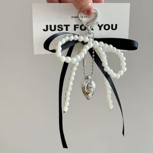 Pearl bowknot keychain detail, featuring chic black ribbon and silver heart charm for bags.