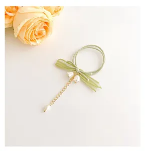 Dettaglio elastico capelli fiocco mughetto verde, accessorio floreale elegante.