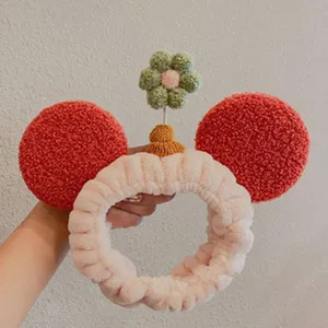 Plush headband detail featuring cute red round ears and a decorative green flower on top.