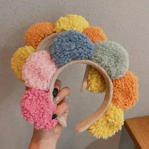 Colorful plush pom-pom detail of the stylish headband showing soft fuzzy texture.