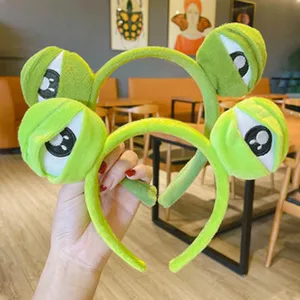 Detailed shot of cute green plush big eye headband, soft and comfortable hair hoop accessory.