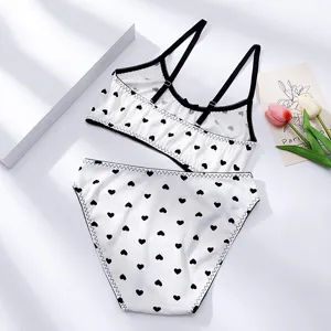 Detailansicht des weißen gerippten Bralette- und Slip-Sets mit schwarzen Herzchen.