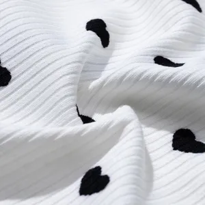 Nahaufnahme des weissen Rippstrickstoffs mit niedlichem schwarzen Herzmuster-Print.
