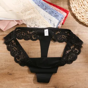 Détail en gros plan d'un string noir en dentelle avec broderie florale et étiquette.