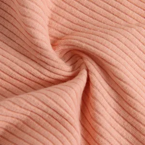 Close-up detail of soft ribbed knit fabric, solid peach pink color texture presentation.