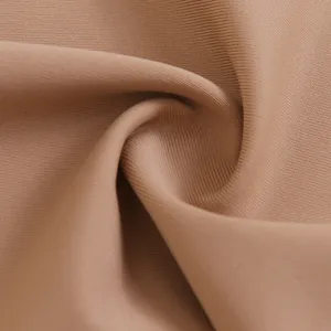 Primo piano dettagliato di tessuto elasticizzato color carne con trama fine e morbida.