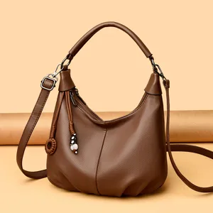 Soft leather brown crossbody hobo bag detail, smooth zipper, delicate woven charm and metal hardware.