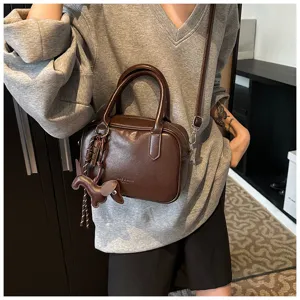 Detailaufnahme einer retro braunen Boston Handtasche mit Hundianhänger, lässige Umhängetasche.