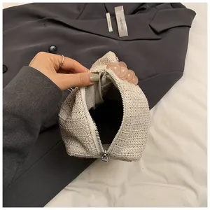 Nahaufnahme der strohgeflochtenen Kosmetiktasche mit Innenreißverschluss und Perlenhenkel.