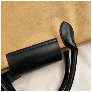 Braune Wildleder-Tasche Detail, mit schwarzen Ledergriffen und stilvollem Kontrast-Design.