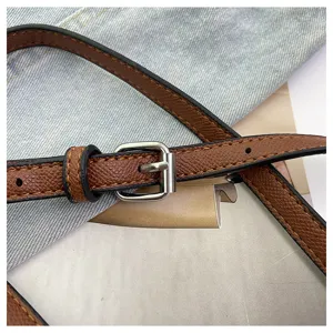 Nahaufnahme eines braunen Leder-Taschenriemens mit Silberschnalle und feinen Nähten.