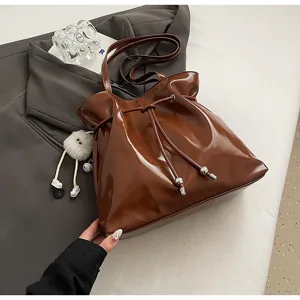Braune Lackleder Schulter-Tragetasche mit Kordelzugverschluss und niedlichem Plüschpuppen-Anhänger.
