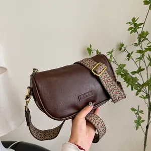 Detailansicht der braunen Schultertasche im Vintage-Stil mit breitem, gemustertem Riemen.